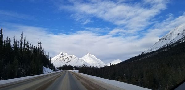 Road amidst snowcapped mountains against sky