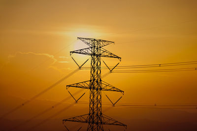 Silhouette electricity pylon against sky during sunset