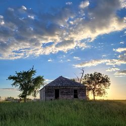 House on field against sky during sunset