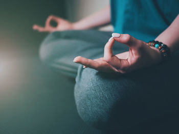 Midsection of woman meditating while sitting on floor