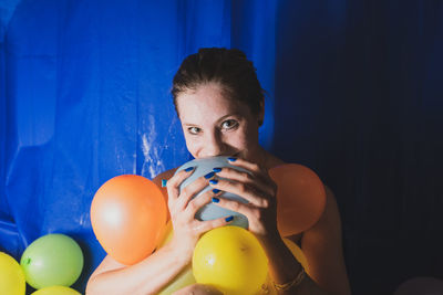 Portrait of woman with colorful balloons at home