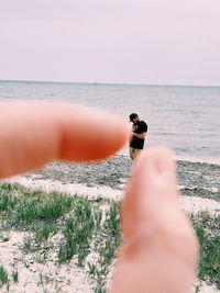 Midsection of person on sea shore against sky