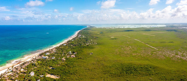 Aerial tulum coastline by the beach with a magical caribbean sea and small huts by the coast.