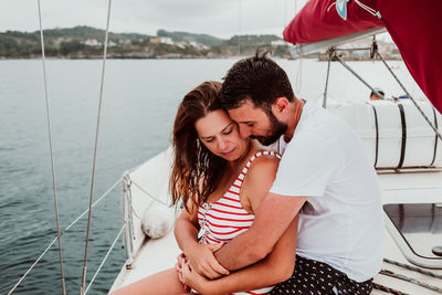 Couple embracing while sitting on boat in sea