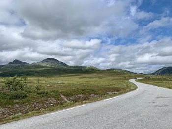 Empty road by mountain against sky