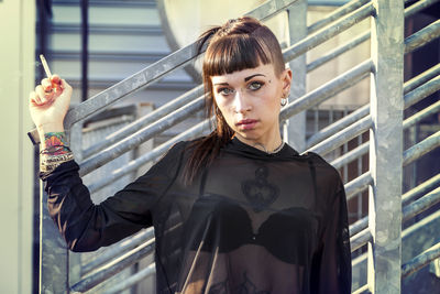 Portrait of young woman standing against wall