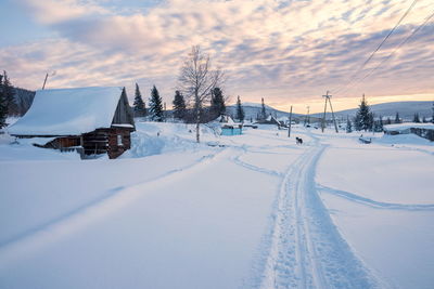 Winter evening landscape of the outskirts of the village with a hut in the foreground