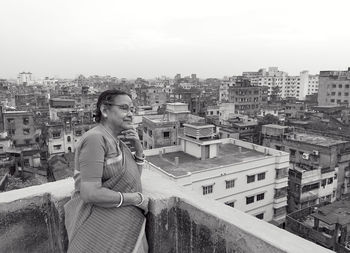An aged bengali woman enjoying view of urban surroundings from rooftop of a building at howrah india