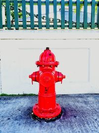 Red fire hydrant on footpath against wall