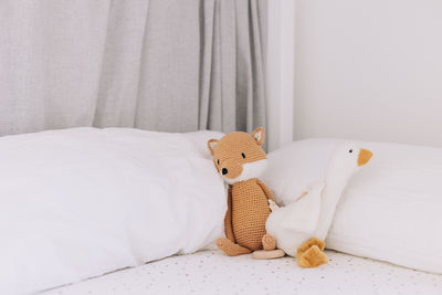 Stuffed animals sitting on a white bed in a child's room