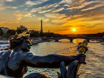 Sculpture of river against buildings during sunset