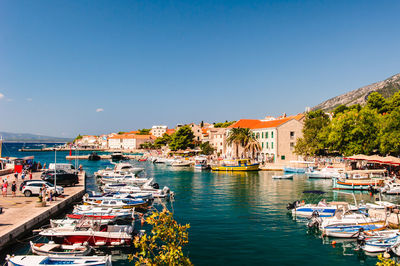Boats moored in harbor against buildings in city