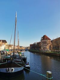 Sailboats moored at harbor against clear blue sky