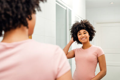 Smiling teenage girl looking in mirror at bathroom