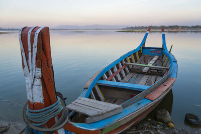 Fishing boat moored on beach against sky