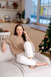 Cute woman using smartphone to call family on christmas eve. talks to relatives