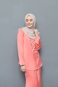 Portrait of smiling young woman standing against white background