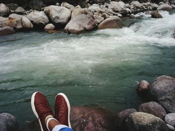 Low section of man on rocks by river