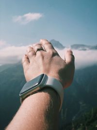 Close-up of man hand on rock against sky