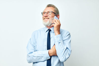 Portrait of young man talking on phone against white background