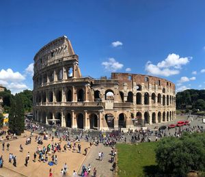 Tourists outside coliseum against sky