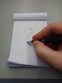 Cropped image of person holding paper against wall