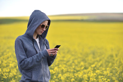 Close-up of woman holding phone while standing on field