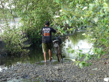 Rear view of man with bicycle in forest