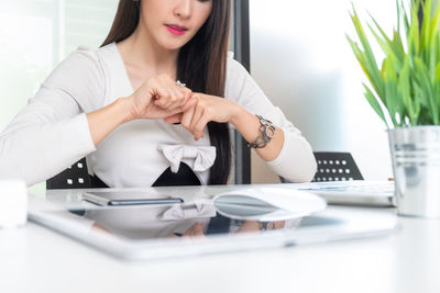 Midsection of woman using mobile phone on table