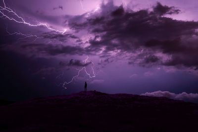 Silhouette man standing on mountain against thunderstorm