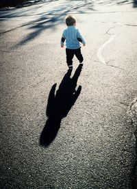 Rear view of boy walking on road