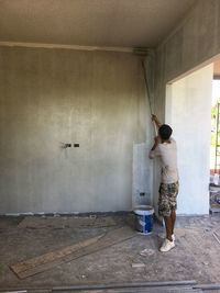 Rear view of woman standing against wall at home