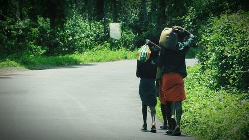 Rear view of men carrying sacks on road