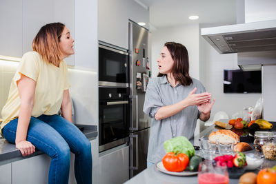 Woman preparing food while standing with friend in kitchen