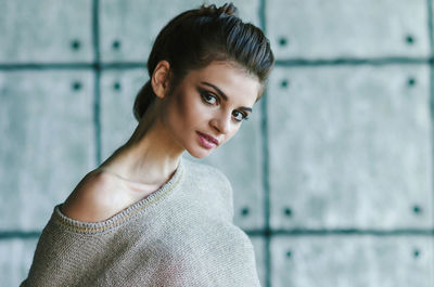 Portrait of smiling young woman against wall