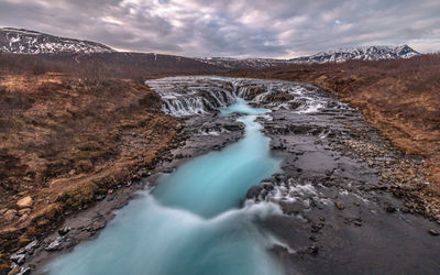 Panoramic view of multiple waterfalls with unique blue water color