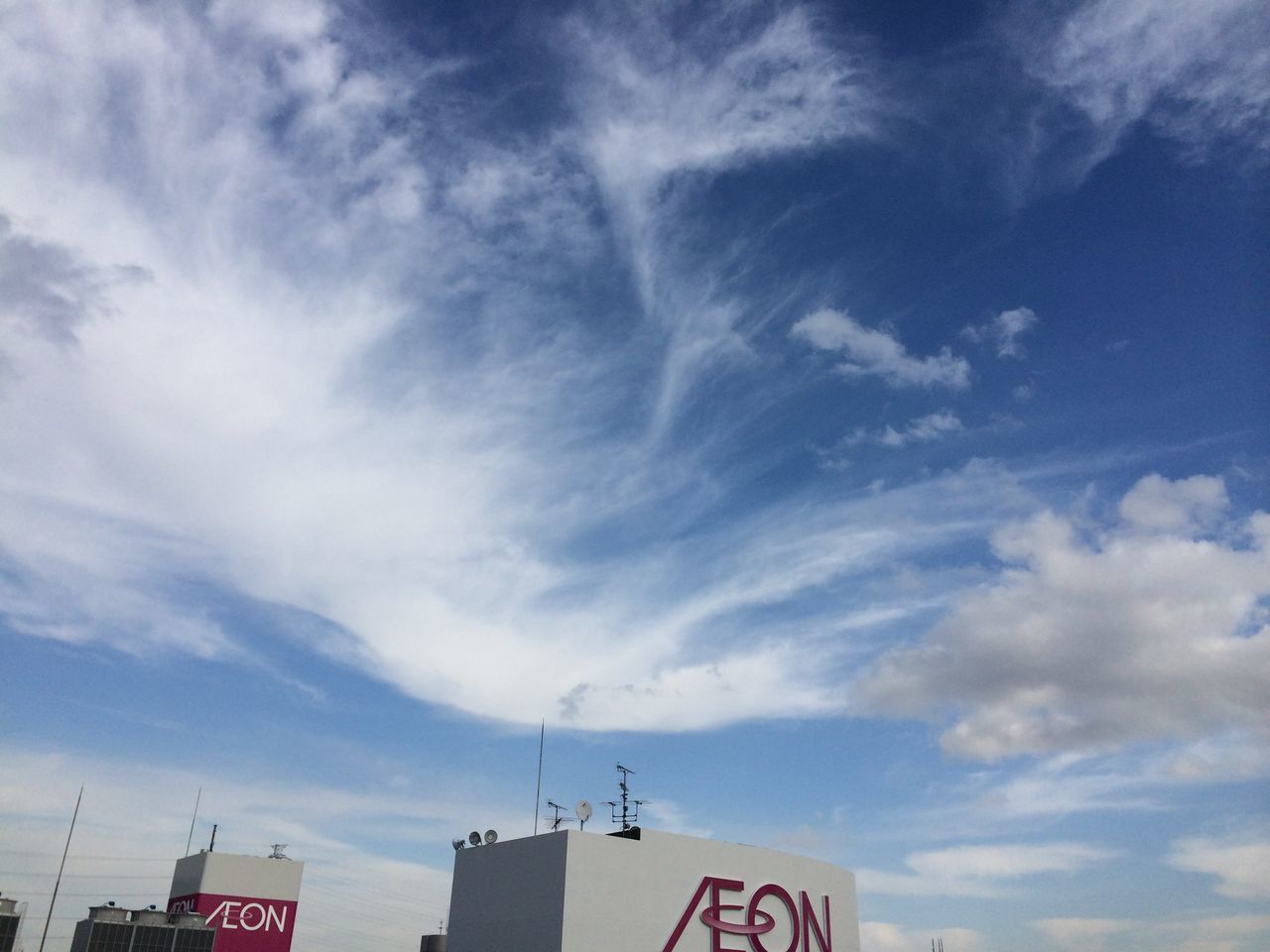 low angle view, sky, built structure, architecture, building exterior, cloud - sky, communication, text, high section, cloud, cloudy, day, outdoors, no people, western script, part of, building, city, blue, roof