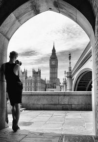 Rear view full length of man photographing big ben while standing at archway in city