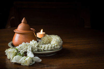 Clay pot with candle and garland on plate