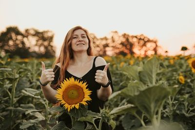 A young woman holds sunflowers.