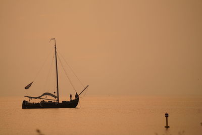 Silhouette sailboat in sea against sky during sunset