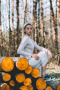 Young woman sitting on log in forest