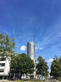 Low angle view of trees and buildings against blue sky