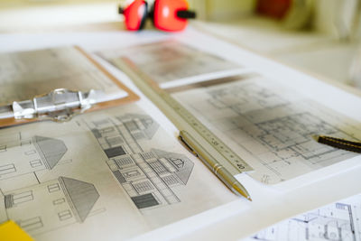 Top view of blueprints, ear defenders, level and tools on architect workspace at construction site