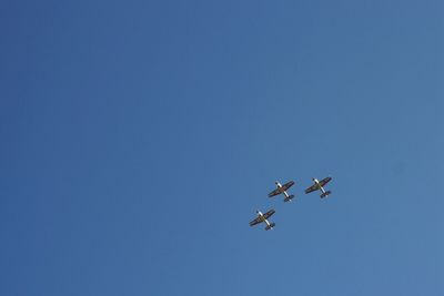 Low angle view of airplane flying against clear blue sky