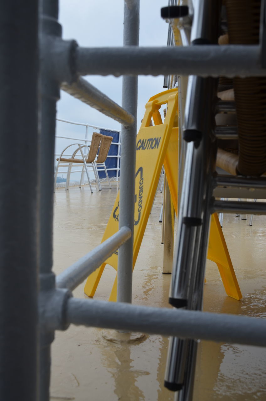 CLOSE-UP OF YELLOW RAILING AGAINST SEA