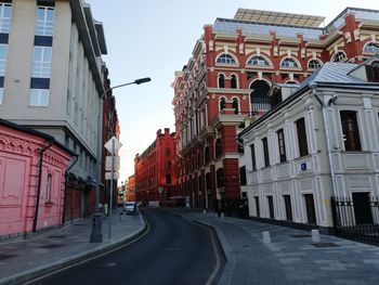 Empty road amidst buildings in city