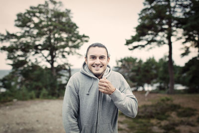 Portrait of smiling young man zipping hooded sweatshirt in back yard