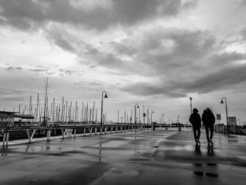 Silhouette people walking on beach against sky