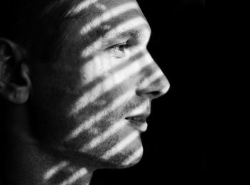 Close-up of man in shadow against black background